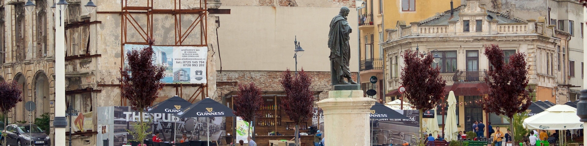 A bustling square with a statue, outdoor seating, and historic buildings.