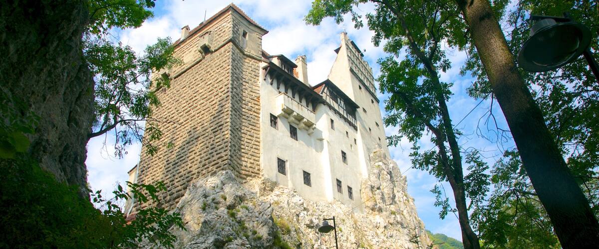 A castle on a rocky cliff with a few people standing on a path.