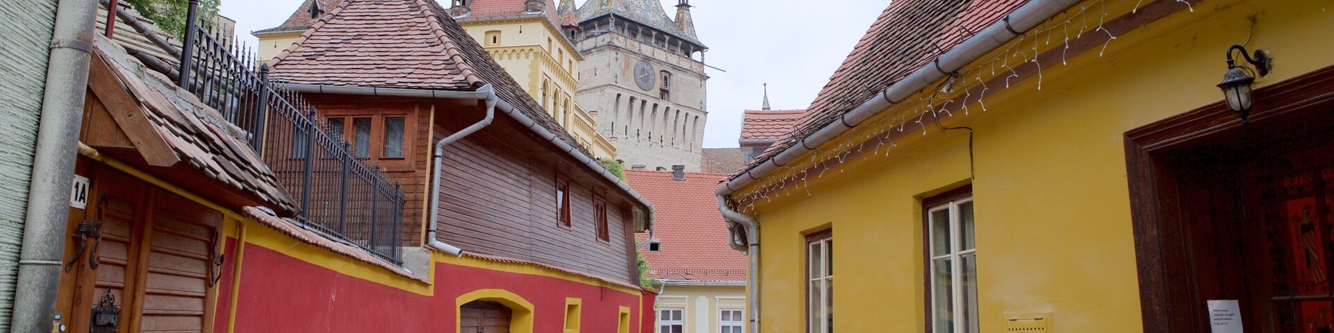 Una calle estrecha con edificios coloridos, una torre del reloj y la aguja de una iglesia.