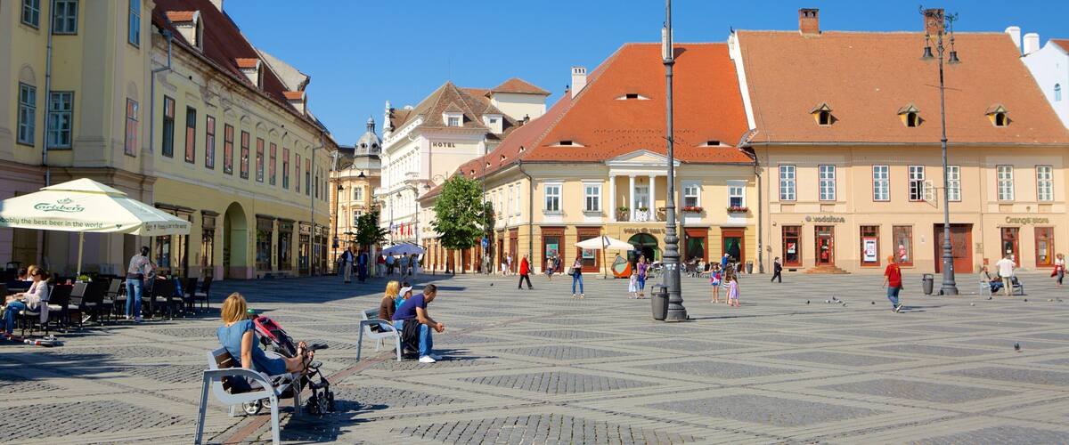 A historic square with cobblestone pavement, traditional European architecture, and outdoor seating areas.
