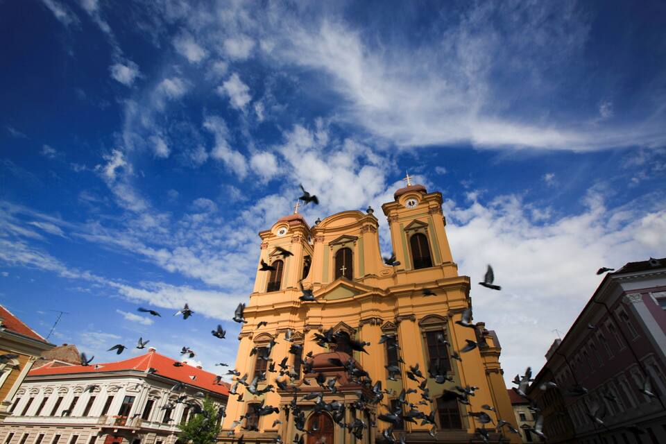 Una iglesia histórica con arquitectura ornamentada y palomas volando.
