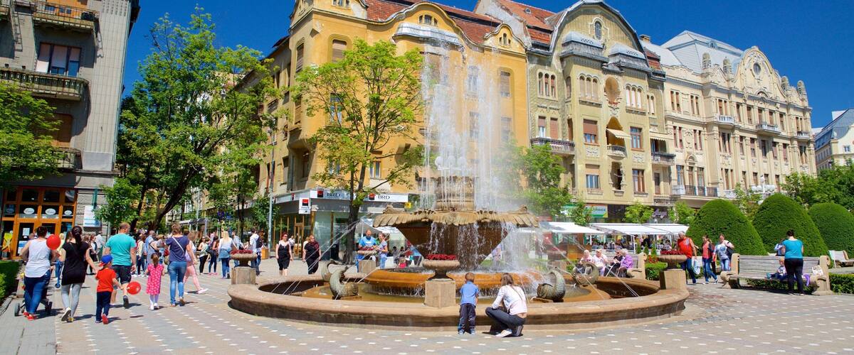 A public square with a fountain, surrounded by historic buildings with ornate facades.