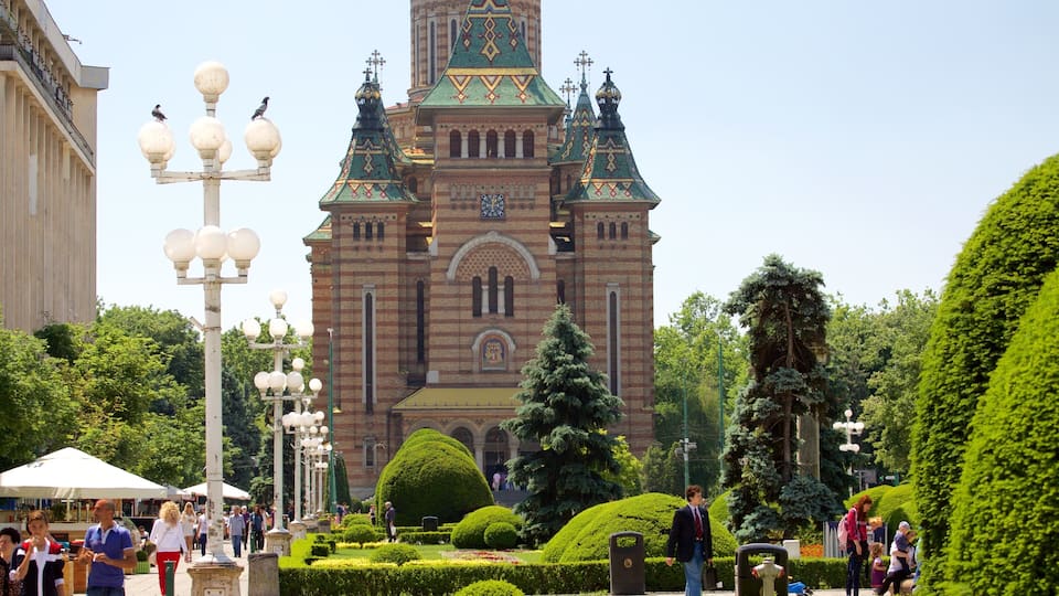 A historic building with a clock tower, surrounded by well-manicured gardens and a bustling street scene.