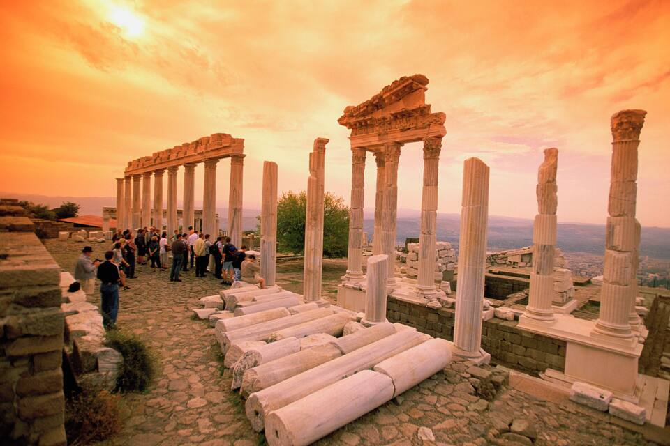Ancient ruins with columns and a crowd of people.