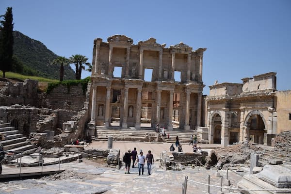 The ruins of an ancient amphitheater with columns and steps, surrounded by visitors.