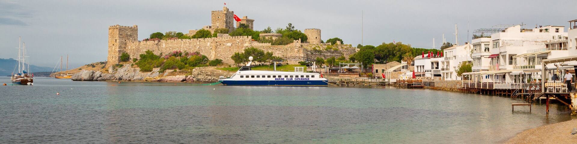 A coastal town with a historic castle, a marina, and a beach.