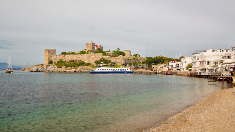 Eine Küstenstadt mit einer historischen Burg, einem Yachthafen und einem Strand.