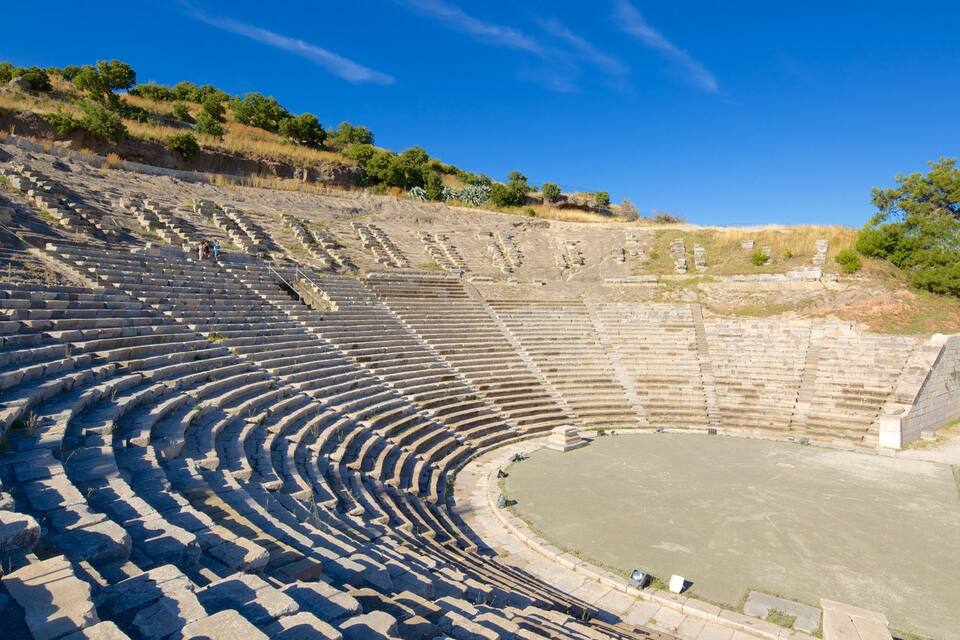 Un antiguo anfiteatro de piedra con asientos y un escenario central.