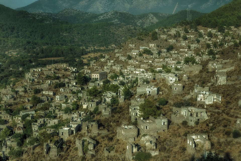 A mountainous village with numerous stone buildings scattered across the hillside.