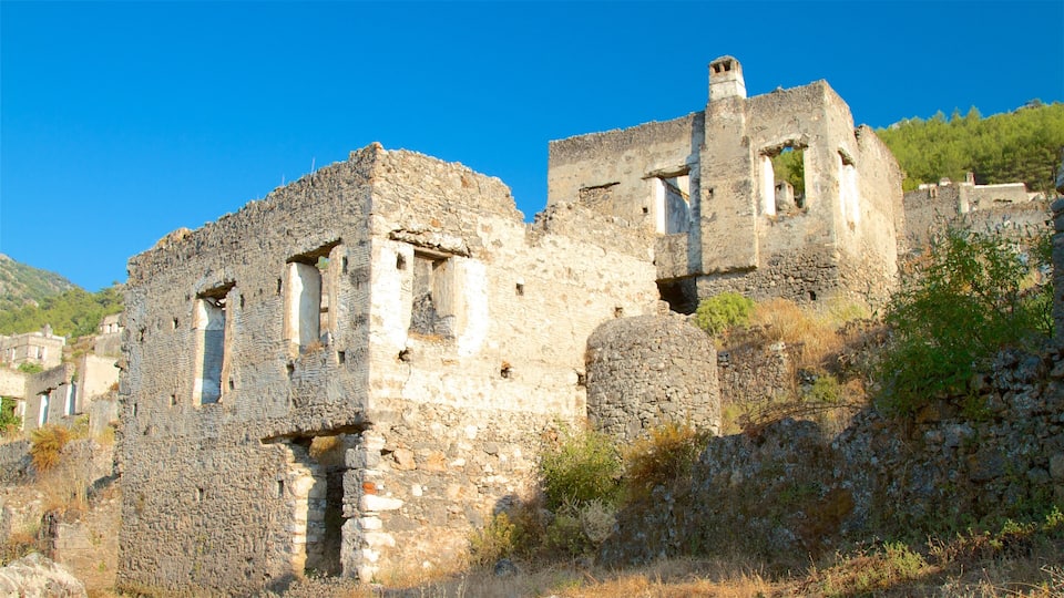 Ancient stone ruins with multiple arches and towers, surrounded by dry vegetation and a clear blue sky.