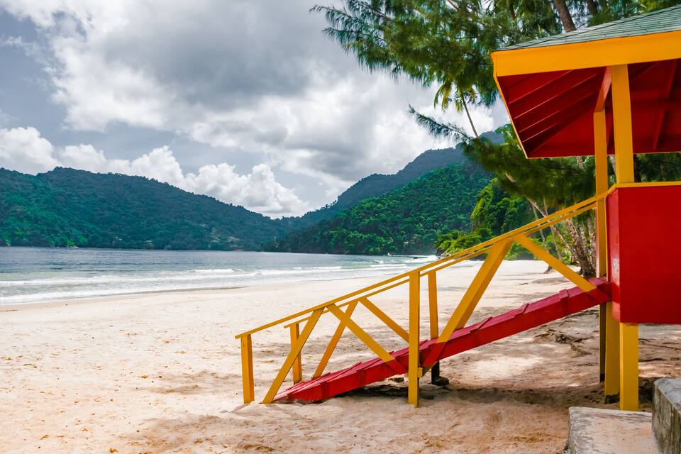 Une plage avec un poste de surveillance pour les sauveteurs, peint en rouge et en jaune, et un escalier menant à ce poste.