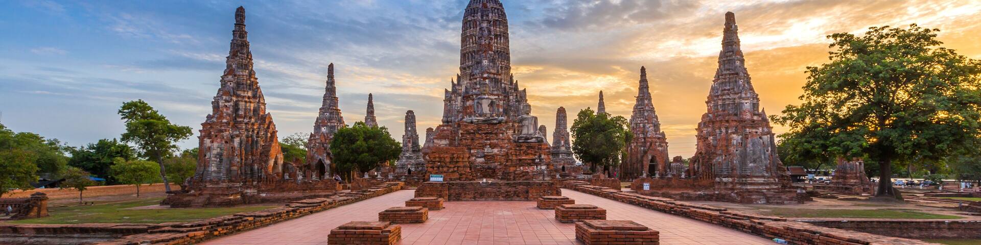 Un ensemble de temples comprenant plusieurs tours à étages et un stupa central, le tout étant entouré d’une cour dallée.