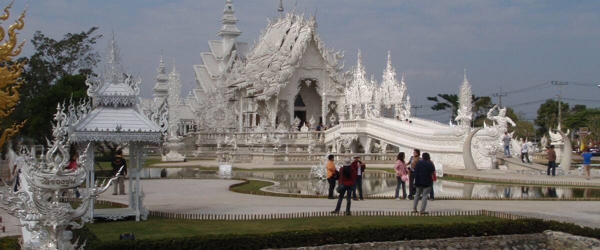 A white ornate temple with a large central building and smaller structures around it.