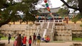 Un edificio coreano tradicional con una escalera de piedra que conduce a él, rodeado de árboles y faroles de colores.