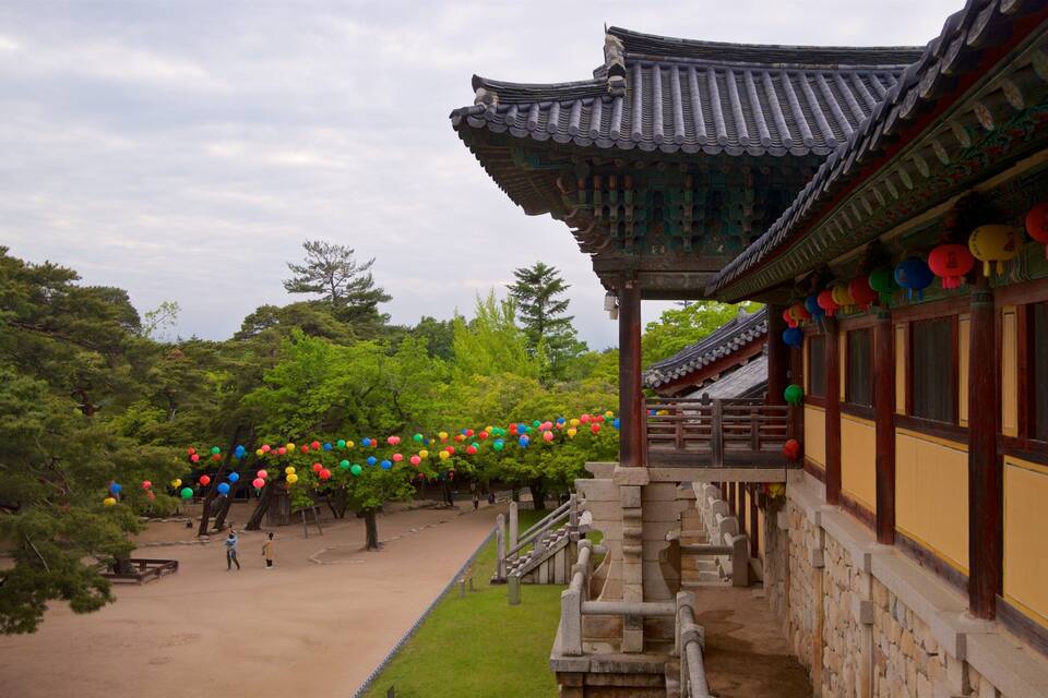 A traditional Korean building with colorful lanterns, surrounded by lush greenery and trees.