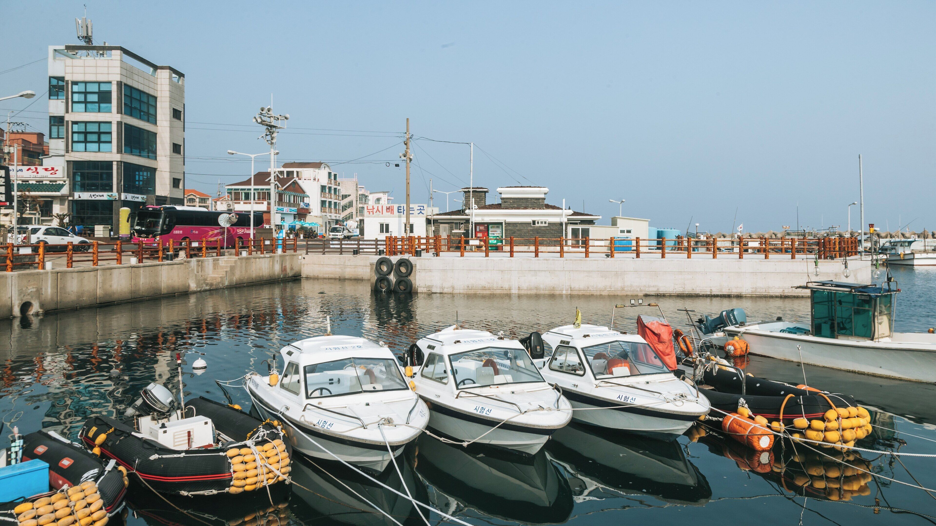Vibrant view of Iho Beach with fishing boats and serene waters in Downtown Jeju City, Jeju, South Korea during a sunny day