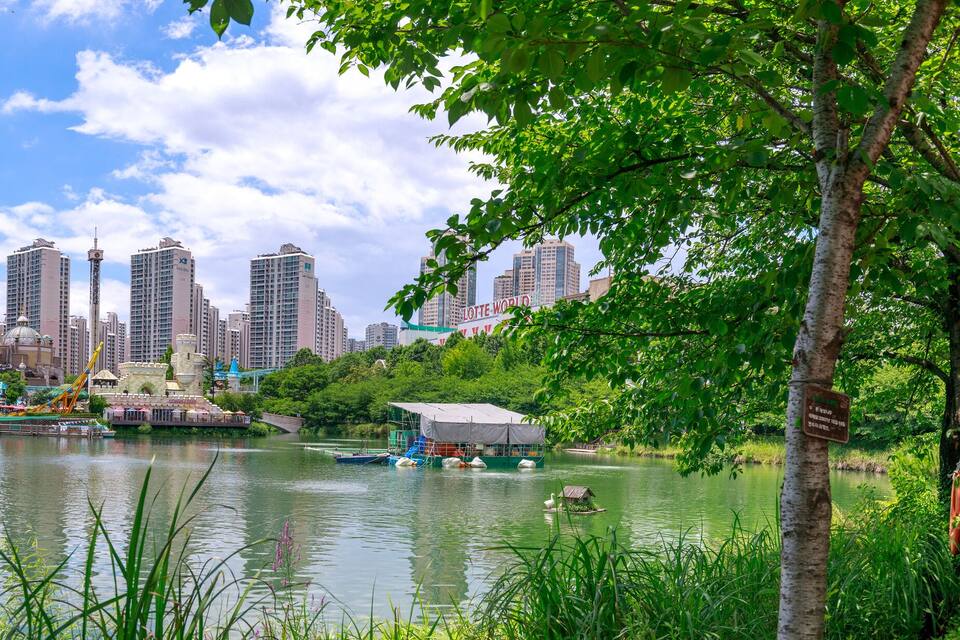 A river with boats, a city skyline, and a park with trees.
