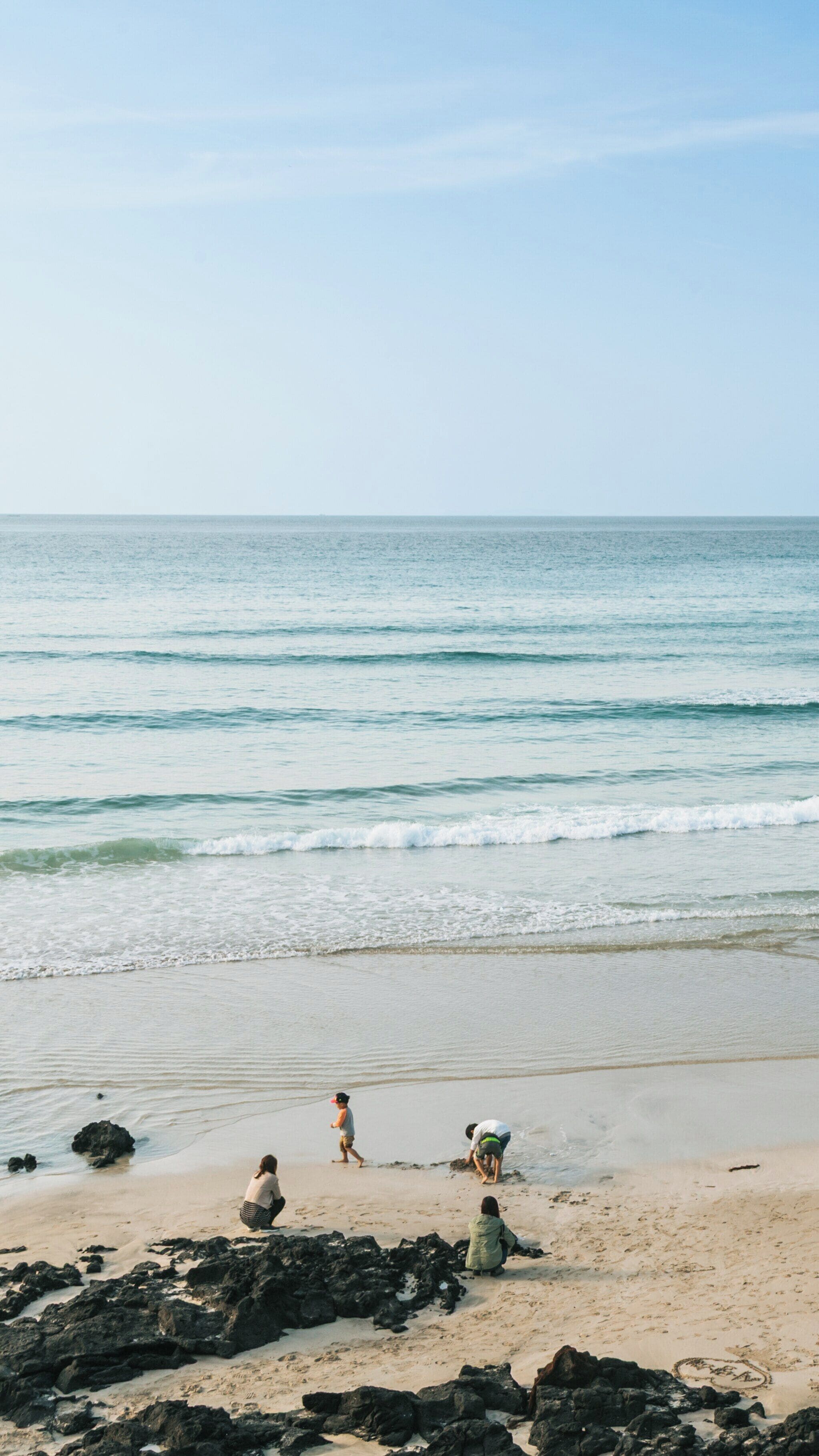 Stunning view of Hamdeok Beach in Jeju City, South Korea showcasing clear skies and calm waters frequented by visitors enjoying leisure activities