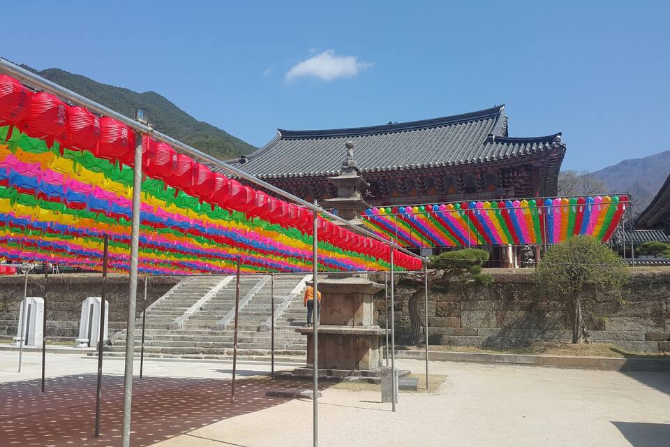Un bâtiment traditionnel avec un toit en tuiles, des lanternes colorées et des marches en pierre menant à l’entrée.