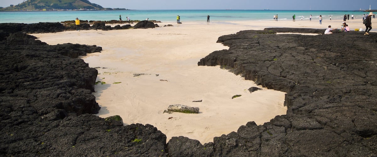 Hyeopjae Beach showing a sandy beach, rocky coastline and general coastal views