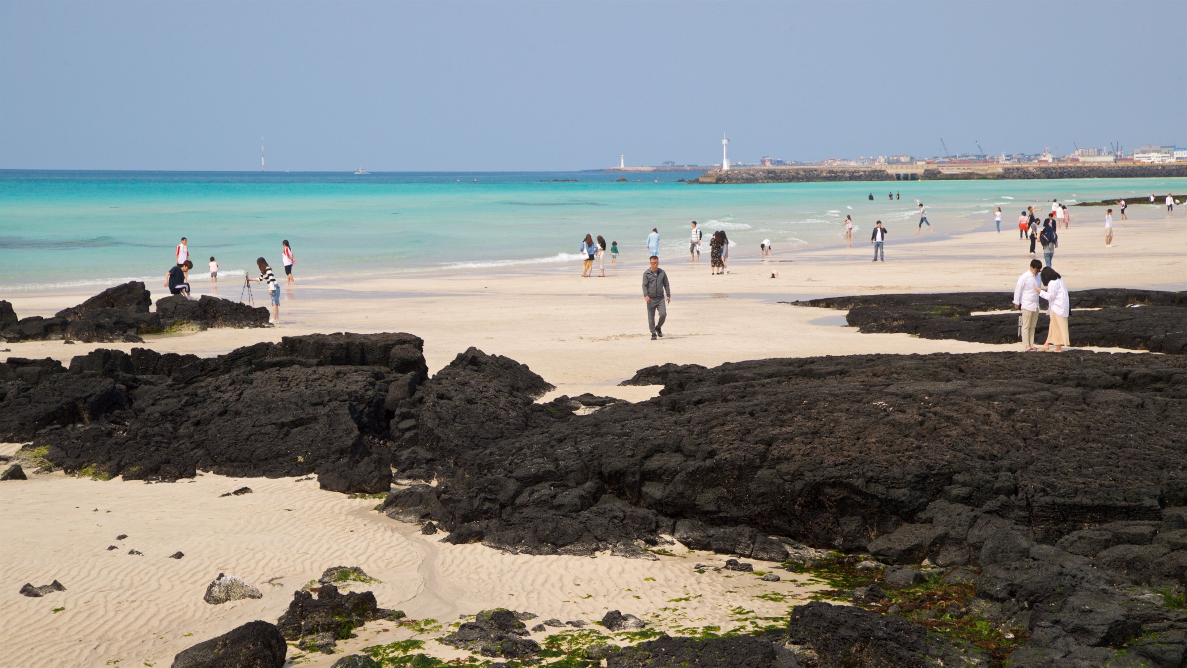 Hyeopjae Beach which includes a beach and general coastal views as well as a small group of people