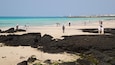 Une plage animée, un phare et une côte rocheuse.