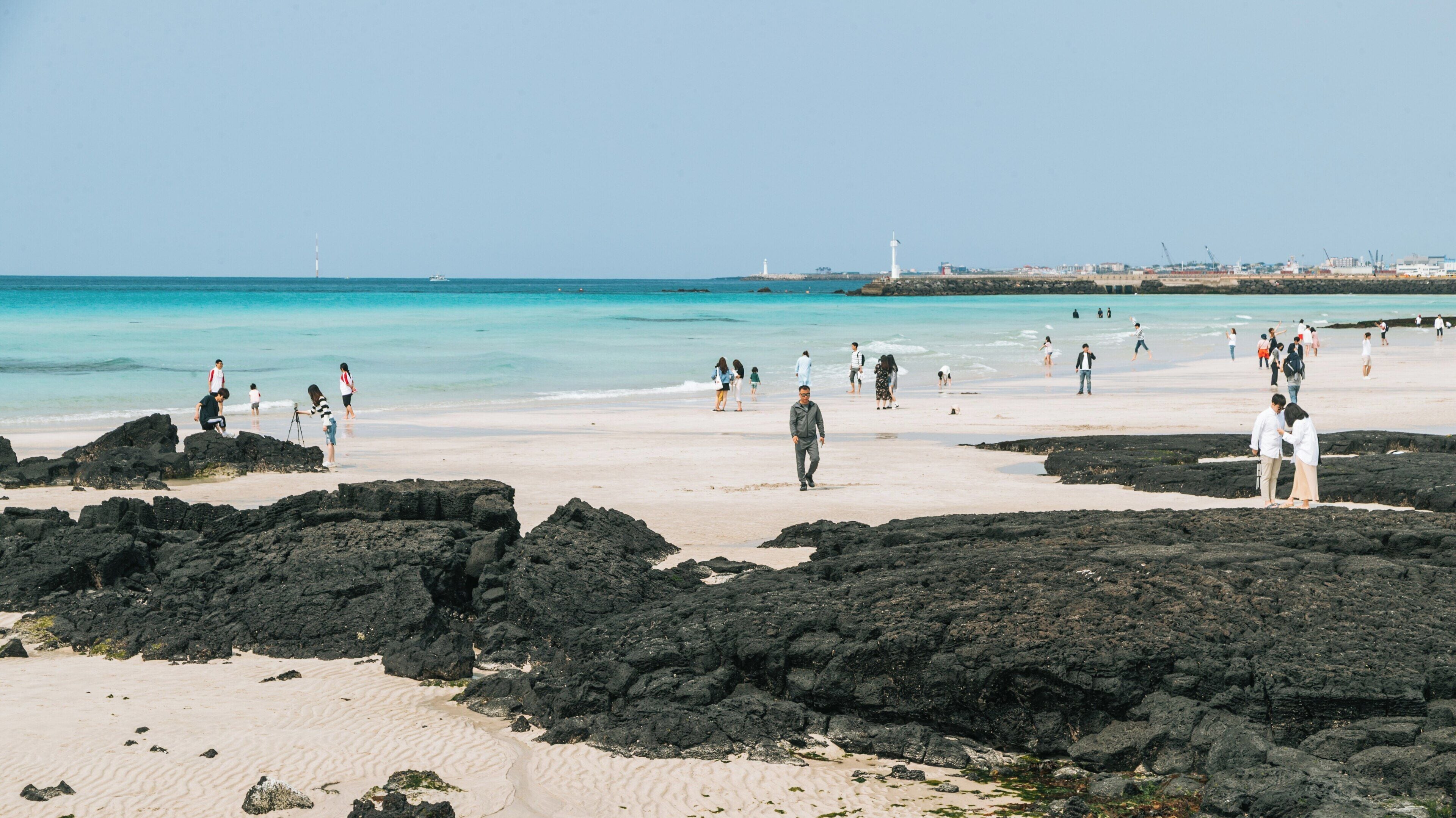 Visitors enjoy sunny day at Hyeopjae Beach in Hallim, Jeju City, South Korea, with clear waters and unique rock formations