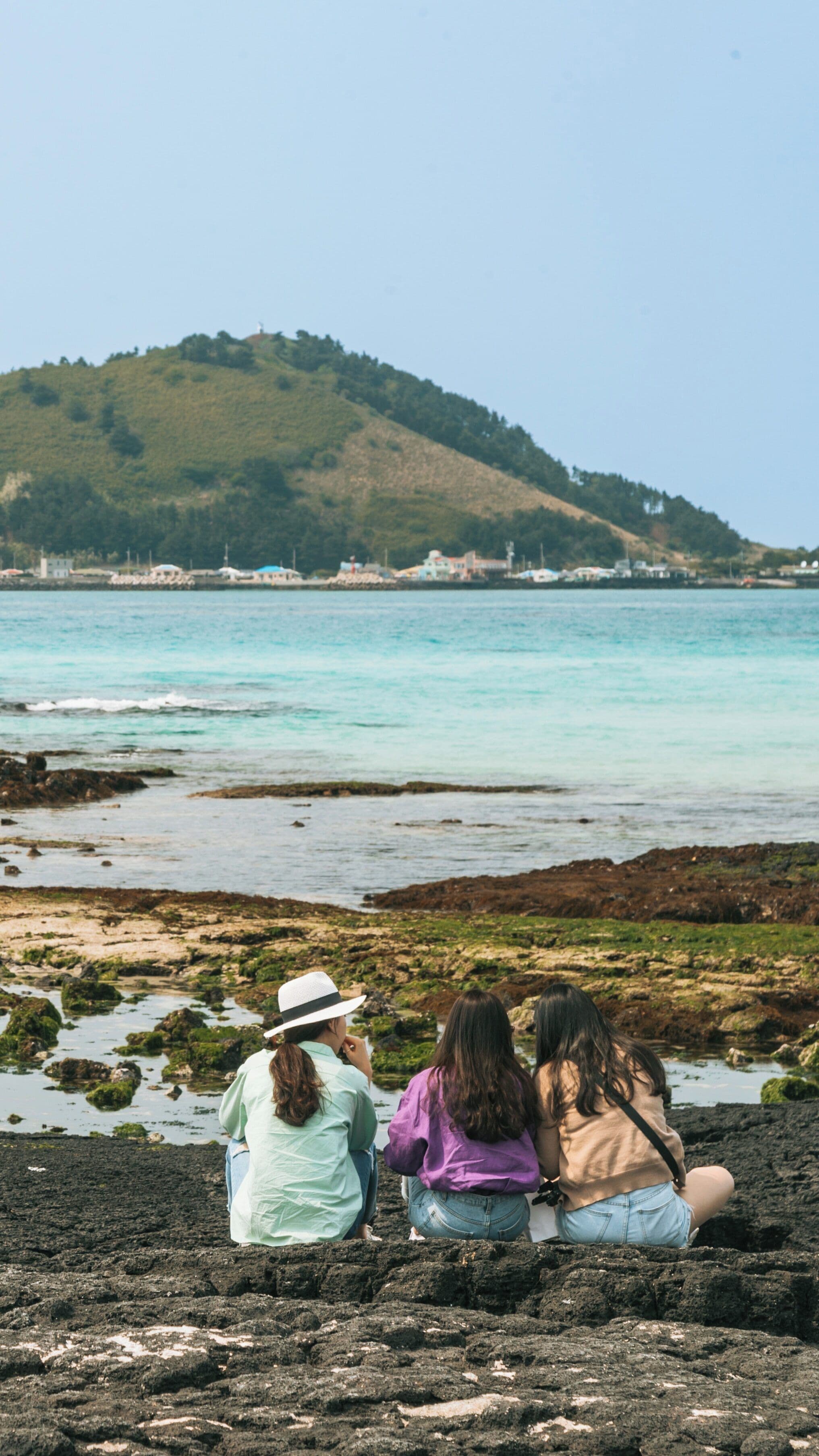 Breathtaking Hyeopjae Beach in Hallim, Jeju City captures visitors enjoying the serene coastal atmosphere on a beautiful day