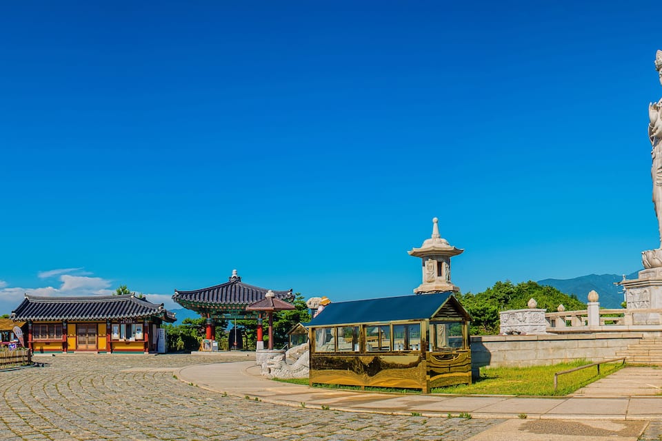 A traditional Korean temple with a large statue and pagoda.