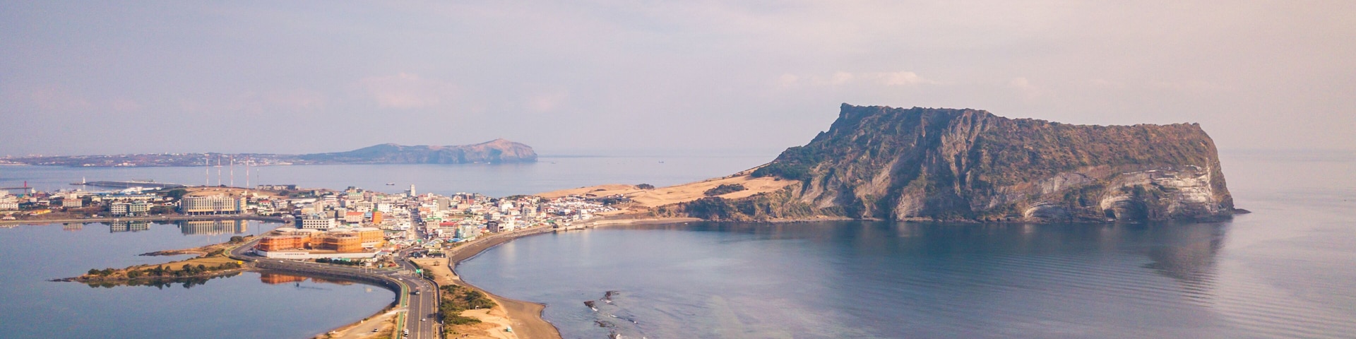 Una ciudad costera con un acantilado imponente, una carretera serpenteante y un mar tranquilo.
