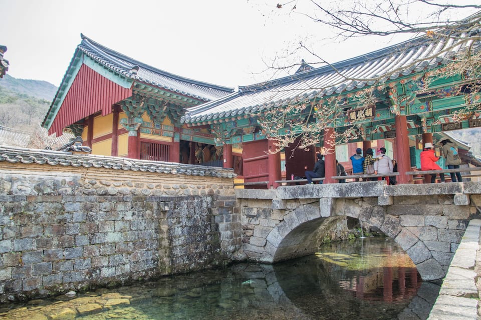 A traditional Korean building with a stone bridge over a waterway.