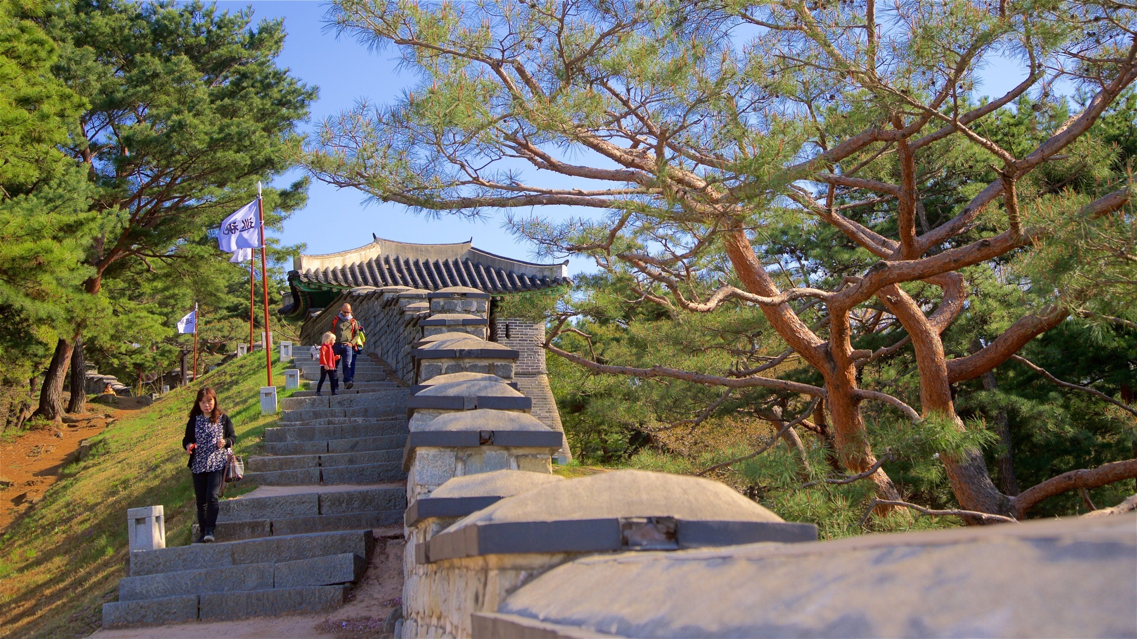 Fortaleza de Hwaseong ofreciendo un jardín y elementos del patrimonio y también un pequeño grupo de personas