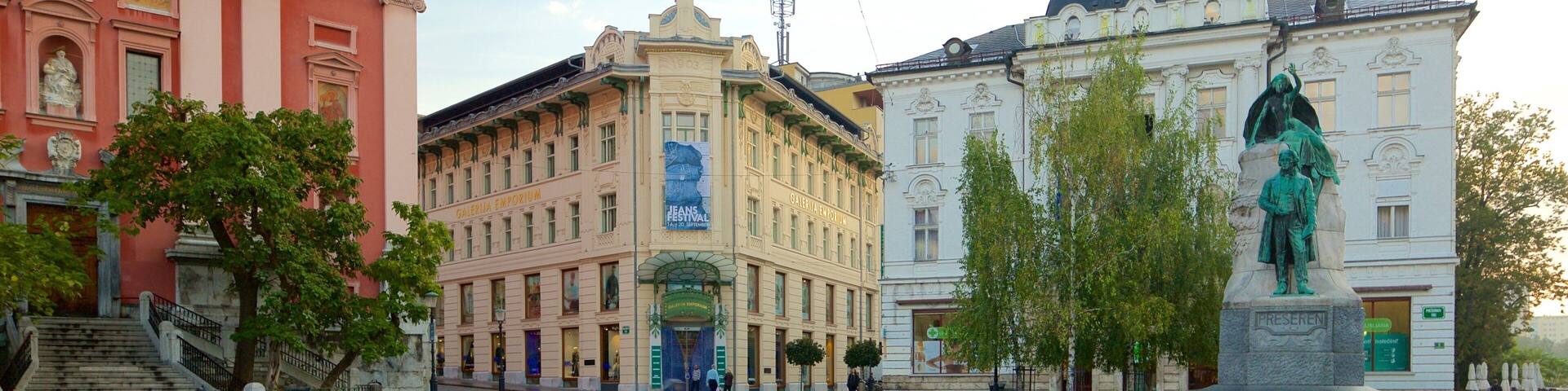 A plaza with a pink building, a yellow building, and a white building with a statue.
