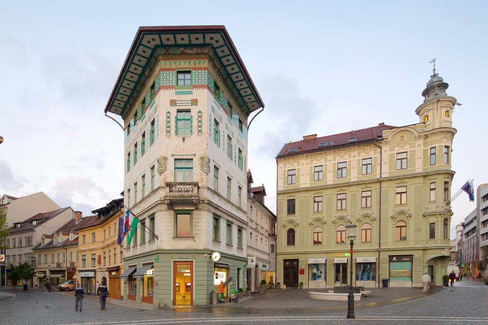 A historic square with a distinctive corner building featuring ornate architecture and a clock tower.
