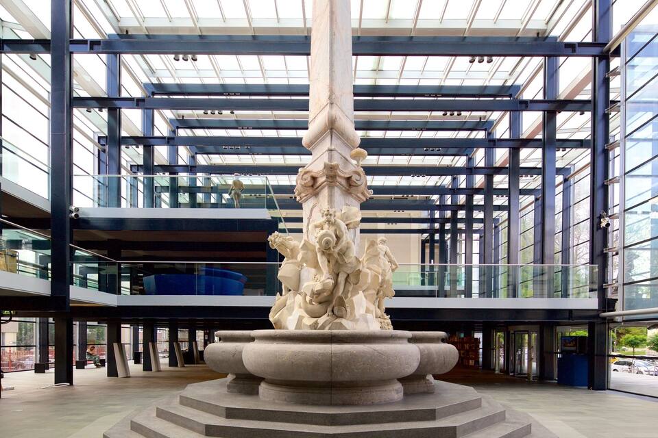Um edifício moderno com uma escultura de coluna central e guarda-corpos de vidro.