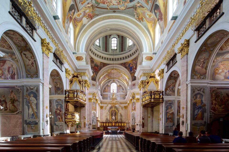 An ornate church interior with high ceilings, detailed frescoes, and a central altar.