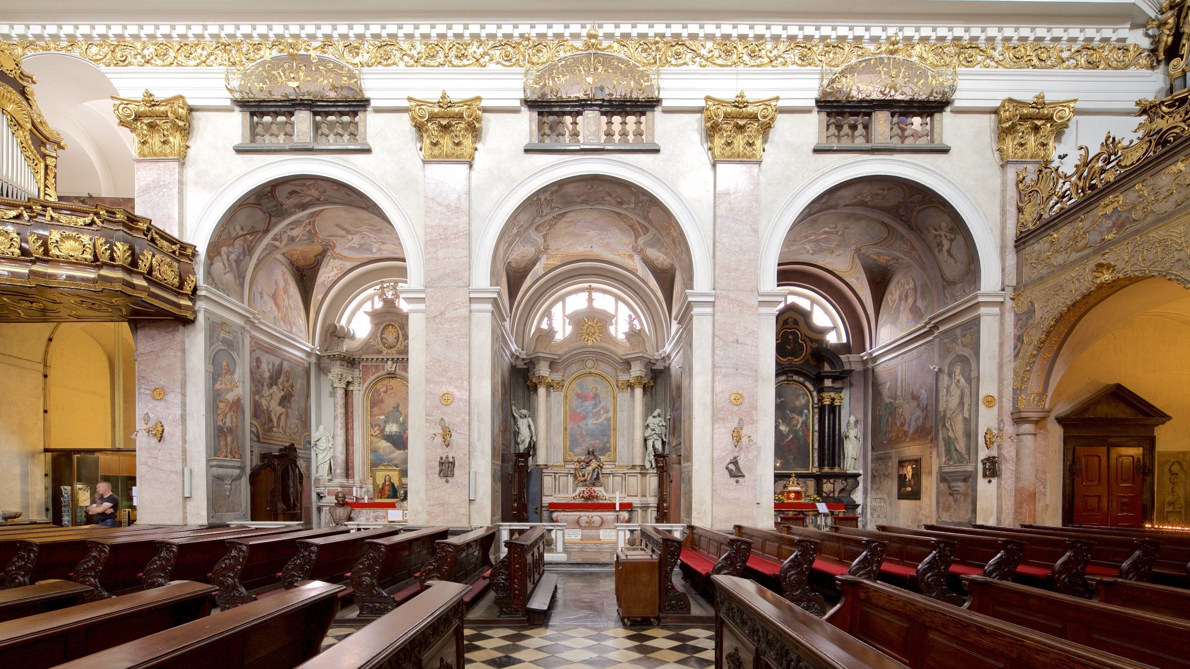 Een versierd kerkinterieur met hoge gewelfde plafonds, gedetailleerde fresco's en een centraal altaar.