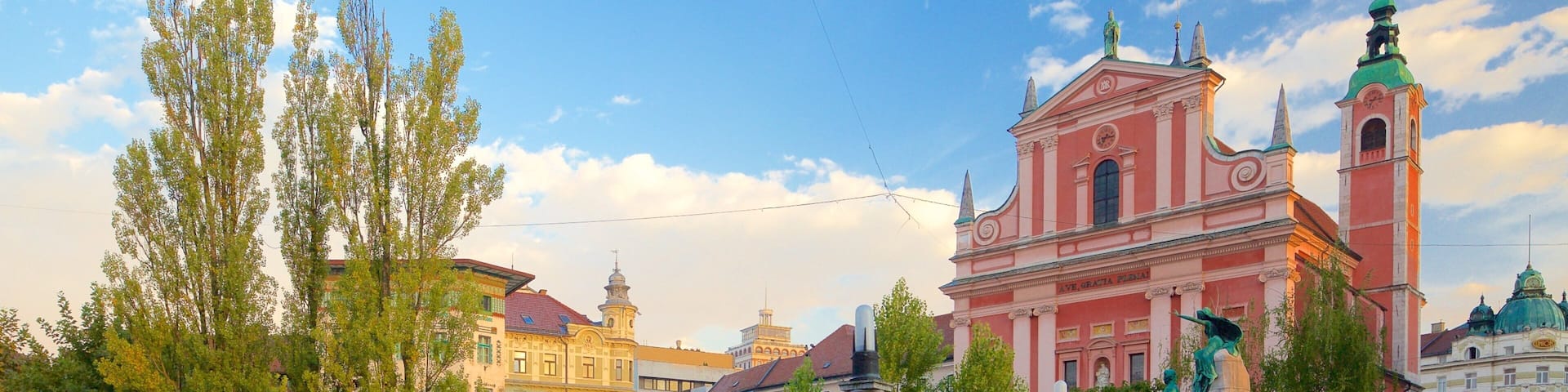 A bridge with ornate balustrades, a pink church with a green dome, and colorful buildings in the background.