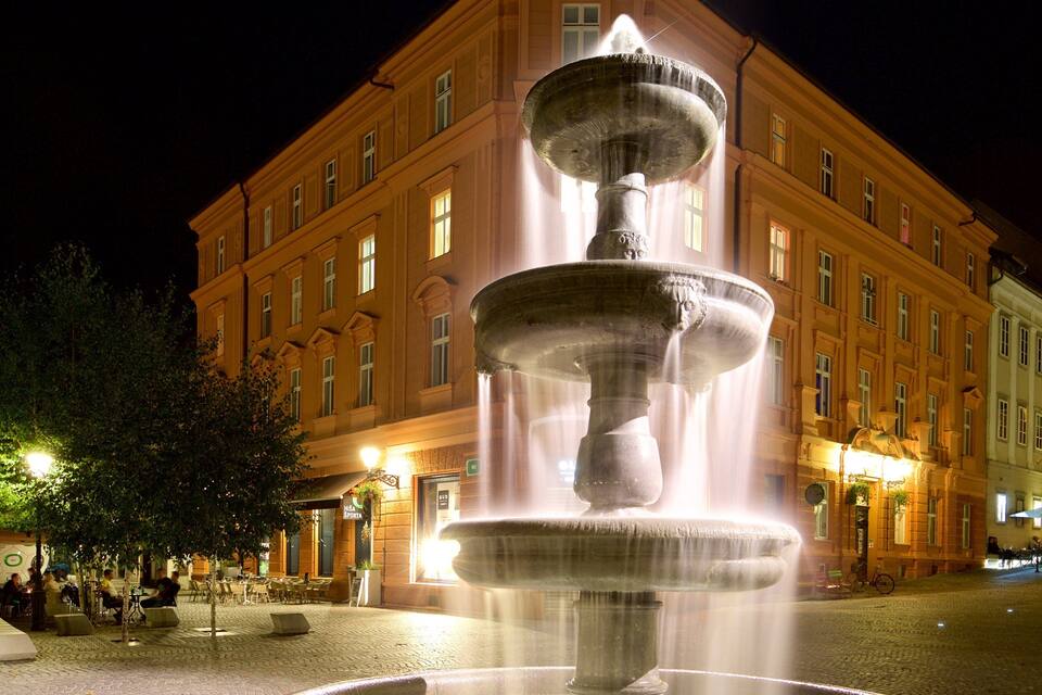 A multi-tiered fountain in a square with a building in the background.