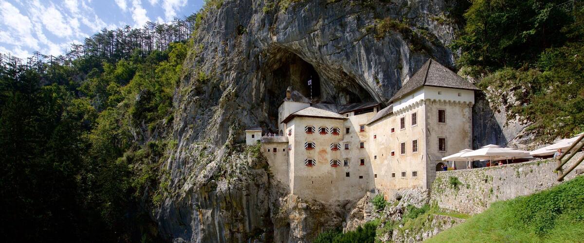 A castle built into a cliffside with a large cave entrance.