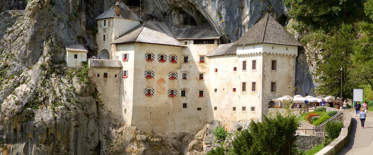 A castle built into a cliffside with a pathway and visitors.