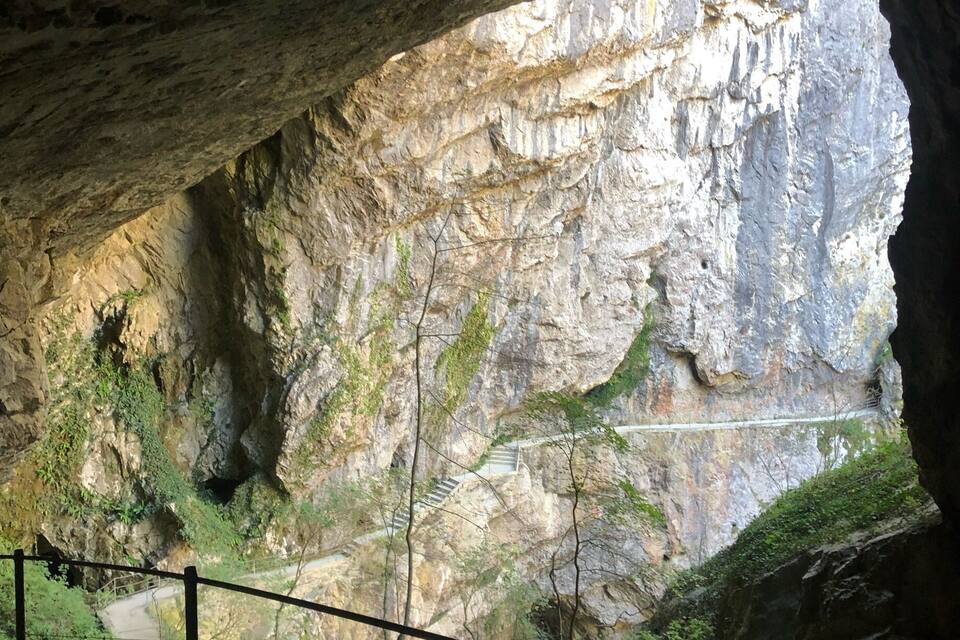 A cave entrance with a rocky interior and a staircase leading into the cave.