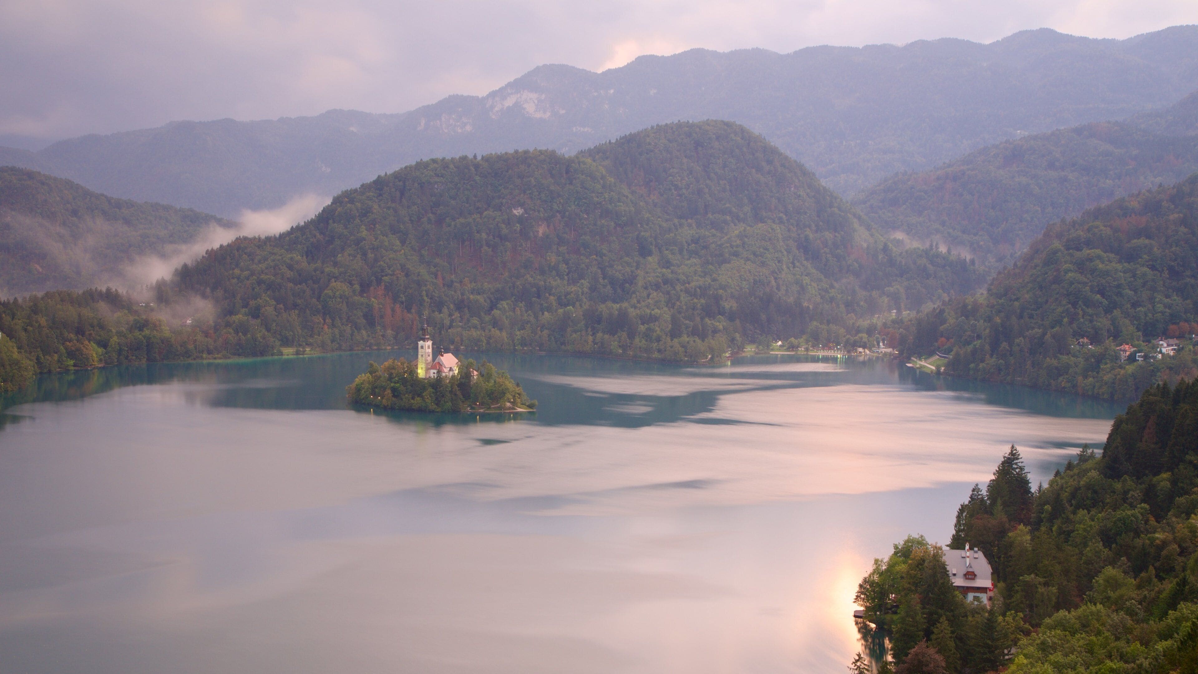 Lake Bled showing a lake or waterhole, mist or fog and mountains