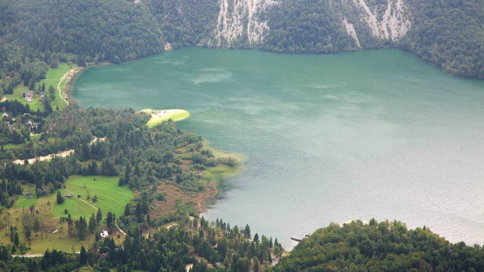 A lake surrounded by forested hills and a golf course.