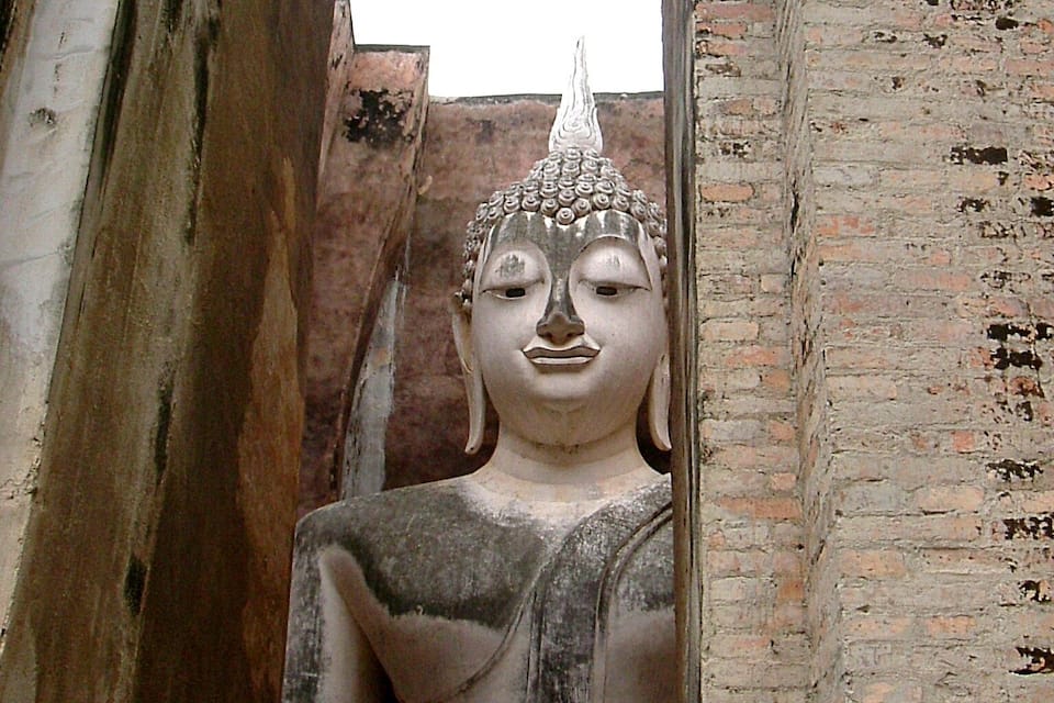 A large Buddha statue in a niche of a brick wall.