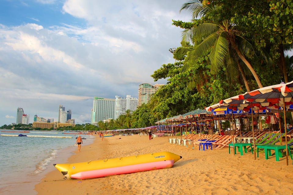 Una playa con palmeras, sillas de playa, sombrillas y un bote hinchable amarillo.