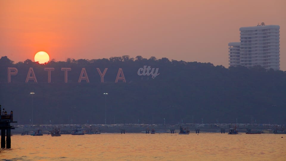 A sunset over Pattaya city with boats on the water.