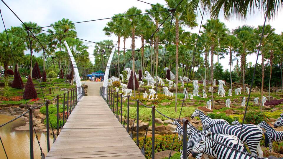 A wooden bridge leading to a zoo with white and black striped zebras and white tigers.