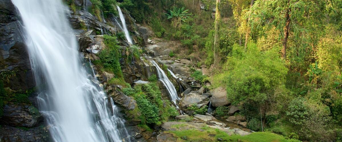 A waterfall cascading over rocks surrounded by lush greenery.