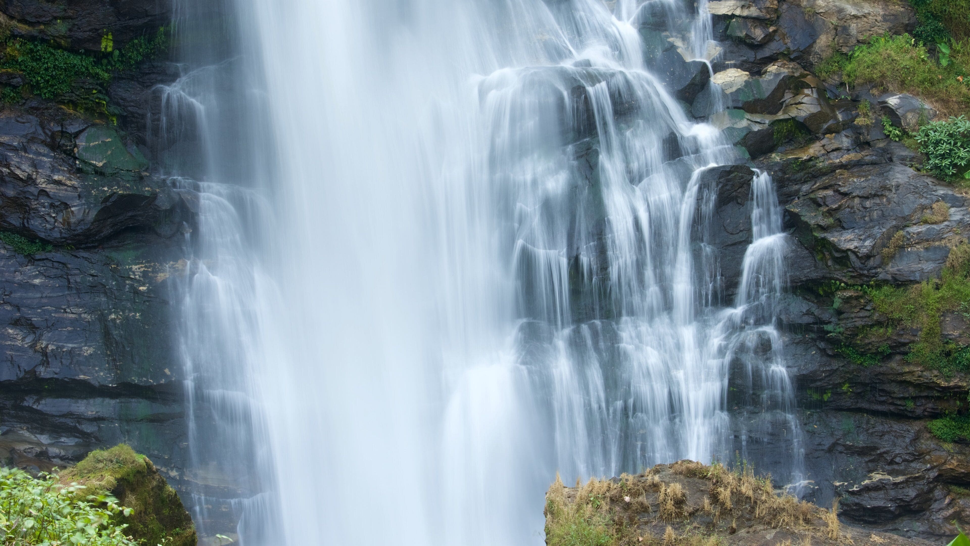 A waterfall cascading over rocky terrain with lush greenery around.